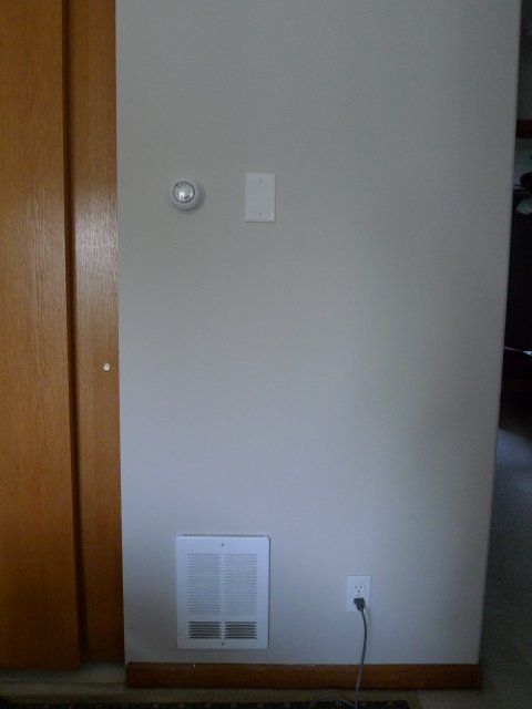 Completed installation, showing new thermostat, cover plate, existing heater.